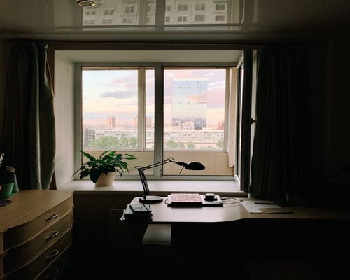 A well-organized desk placed perpendicularly to a large window to minimize direct reflections and glare